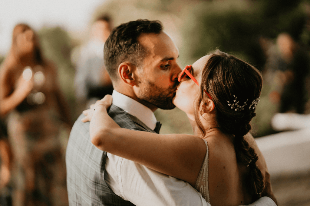 Los novios se besan cariñosamente durante la fiesta de la boda en un espacio exterior.