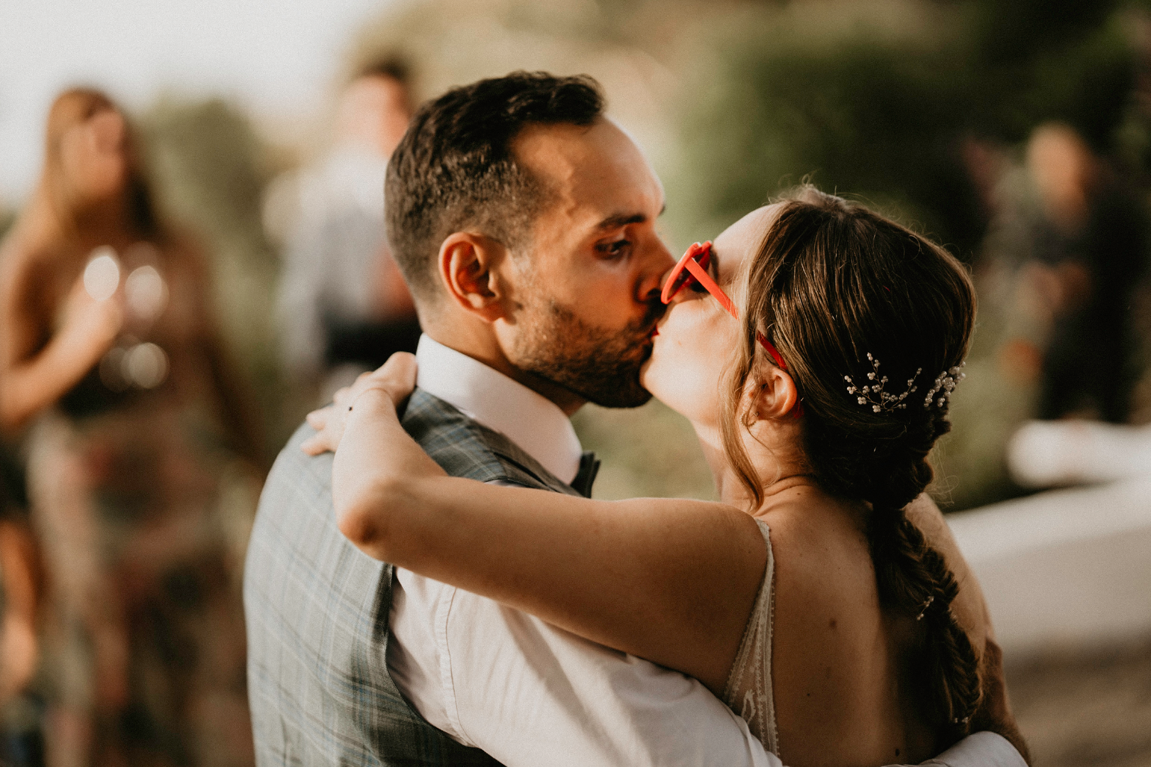 Los novios se besan cariñosamente durante la fiesta de la boda en un espacio exterior.
